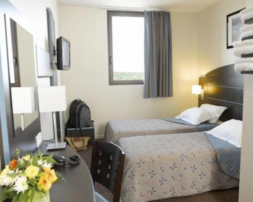 BrensにあるHôtel Akena City Albi Gaillacのベッド2台とテーブルが備わるホテルルームです。