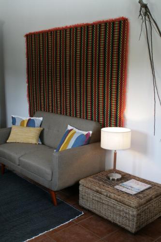 a living room with a couch and a table with a lamp at Casinha à Porta in Arouca