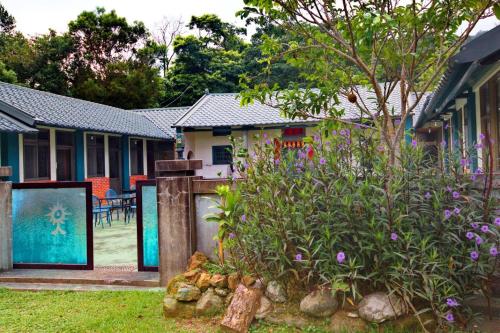 a house with a garden with purple flowers in the yard at Yellow Stone M.V. in Sanyi
