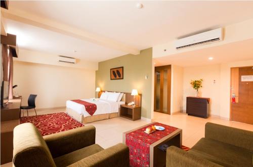 a hotel room with a bed and a living room at Hotel Luwansa Palangkaraya in Palangkaraya