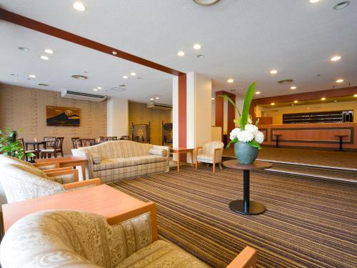 a lobby with couches and a table with flowers on it at Hotel Pearl City Akita Kawabata in Akita