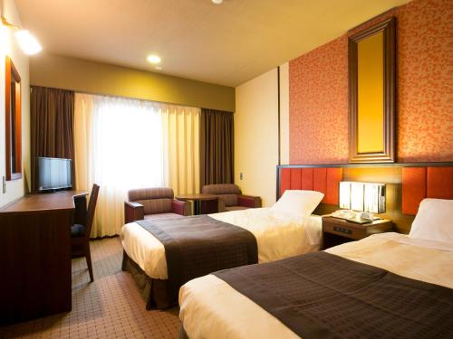 a hotel room with two beds and a television at Hotel Pearl City Akita Kawabata in Akita