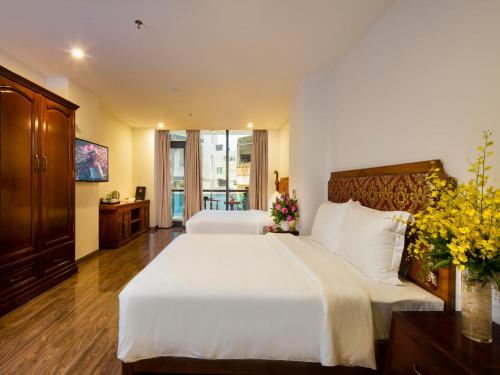 a bedroom with two beds with white sheets and flowers at Red Sun Nha Trang Hotel in Nha Trang