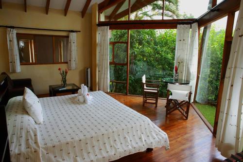 a bedroom with a white bed and a table and chairs at Tenorio Lodge in Bijagua