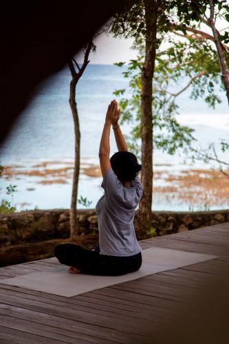 a person doing a yoga pose on a boardwalk at Plataran Menjangan Resort and Spa - CHSE Certified in Banyuwedang