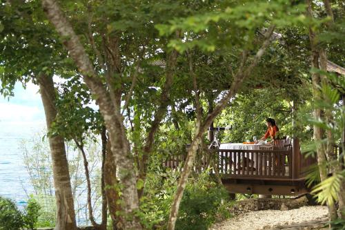 a woman sitting at a table in the woods at Plataran Menjangan Resort and Spa - CHSE Certified in Banyuwedang