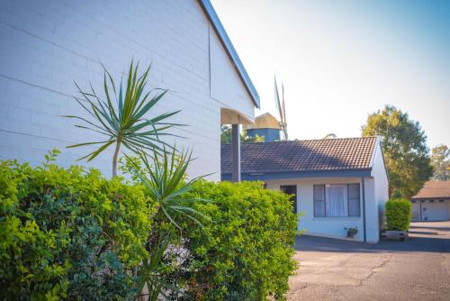 a white building with bushes next to a house at Coffs Windmill Motel in Coffs Harbour