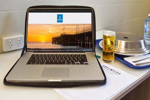 a laptop computer sitting on a table with a glass of beer at Coffs Windmill Motel in Coffs Harbour