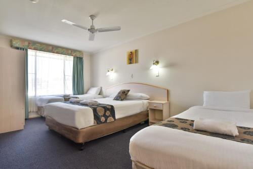 a hotel room with two beds and a window at Coffs Windmill Motel in Coffs Harbour