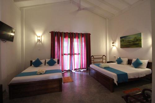 a bedroom with two beds and a window at Santori Unawatuna in Unawatuna