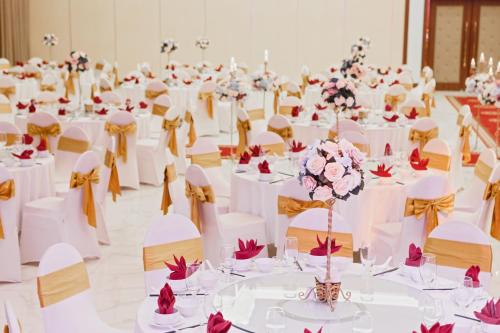 a banquet hall with white tables and chairs and flowers at Muong Thanh Holiday Moc Chau Hotel in Mộc Châu