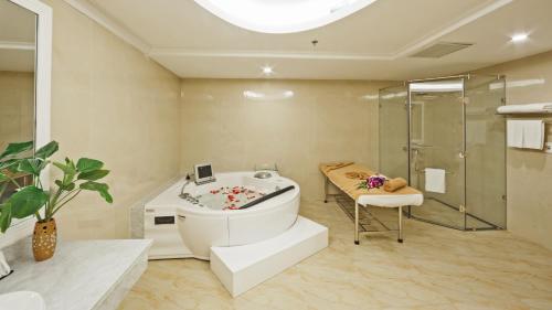 a bathroom with a tub and a glass shower at Muong Thanh Holiday Moc Chau Hotel in Mộc Châu