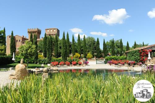 a garden with a pond and flowers and a building at Agriturismo Castello La Grancia di Spedaletto in Pienza