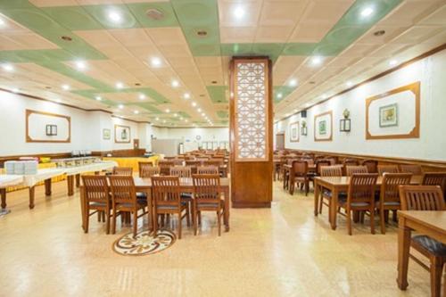 a restaurant with wooden tables and chairs in a room at Bugok Ilsung Condo in Changnyeong