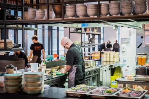 a man standing in a kitchen preparing food at Ibis Styles Hobart in Hobart