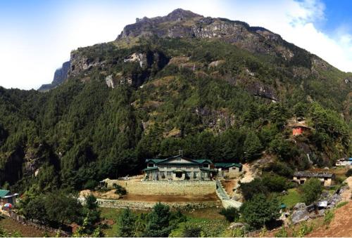 a house on a hill in front of a mountain at Mountain Lodges of Nepal - Monjo in Monjo