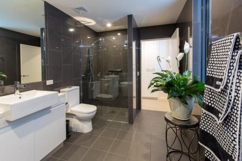 a bathroom with a toilet and a sink and a shower at Luxury Four Bedroom Apartment with Swimming Pool in Wagga Wagga