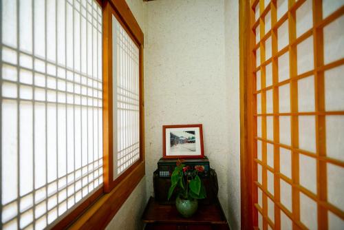 a room with two windows and a vase with a plant at Hanok Dream in Jeonju
