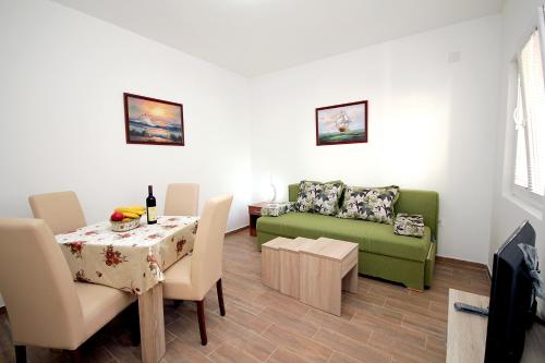 a living room with a table and a green couch at Apartments Centar Sutomore in Sutomore