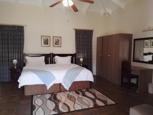 a bedroom with a large bed and a desk at Nooitgedacht Trout Lodge in Lydenburg
