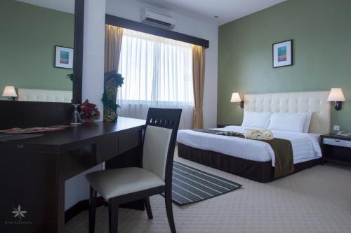 a hotel room with a bed and a desk and a desk at Hotel Seri Malaysia Kepala Batas in Kepala Batas