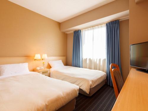 ein Hotelzimmer mit zwei Betten und einem Fernseher in der Unterkunft Hotel Pearl City Akita Kanto-Odori in Akita