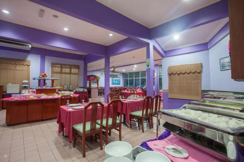 a restaurant with tables and chairs and purple walls at Hotel Seri Malaysia Rompin in Kuala Rompin