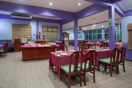 a dining room with tables and chairs and purple walls at Hotel Seri Malaysia Rompin in Kuala Rompin