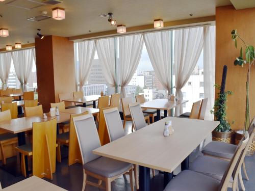 ein Restaurant mit Tischen und Stühlen und großen Fenstern in der Unterkunft Hotel Pearl City Akita Kanto-Odori in Akita