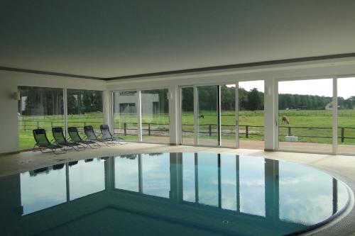 a swimming pool in a house with chairs around it at Friesenhof Hotel-Restaurant-Reitanlage in Trassenheide