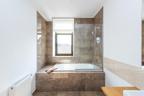 a bathroom with a tub and a window at WISH Aqua&SPA Resort in Vishenki