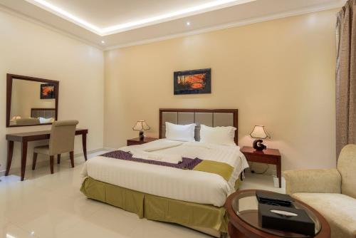 a bedroom with a bed and a desk and a chair at Taleen Al Nakheel Apartment in Riyadh