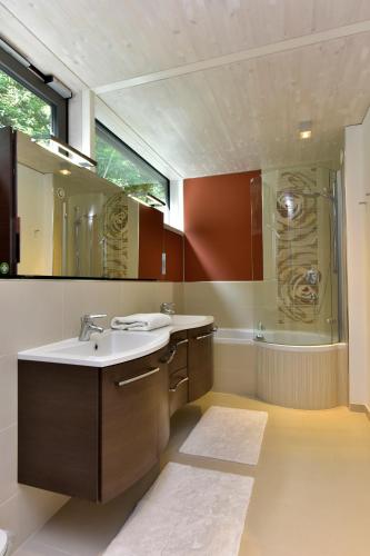 a bathroom with a sink and a mirror and a tub at Glas House - Design Holiday Home in Piesendorf