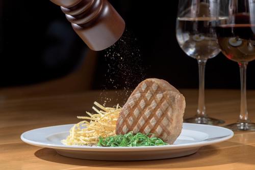 a person sprinkling sauce on a plate of spaghetti at Olympic Palace Hotel in Ixia