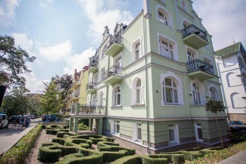 un edificio verde y blanco con un jardín delante de él en Apartamenty Villa Artis en Świnoujście