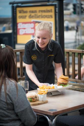 a woman sitting at a table with a sandwich and french fries at Old Colonial, Weston-Super-Mare by Marston's Inns in Weston-super-Mare