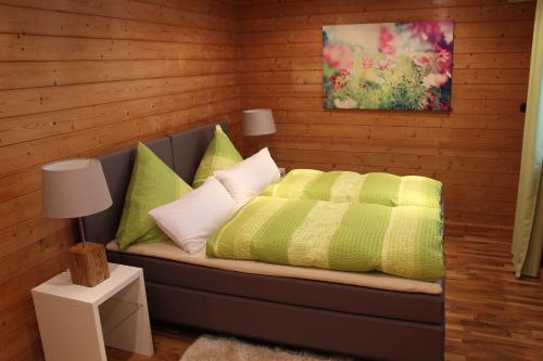 a bedroom with a bed with green and white pillows at Pension Stauber in Hohenburg