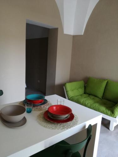 a living room with a table with plates and a green couch at Dammuso SOLMAR in Pantelleria