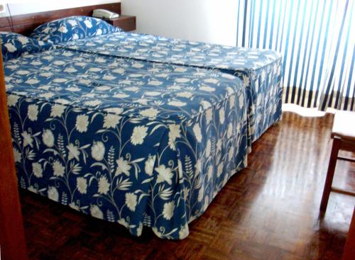 um quarto com uma cama com um cobertor azul e branco em Residencial Habimar em Sines