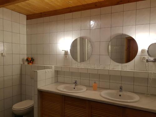 a bathroom with two sinks and a toilet and mirrors at Pension zum Wiesengrund in Frauenhagen