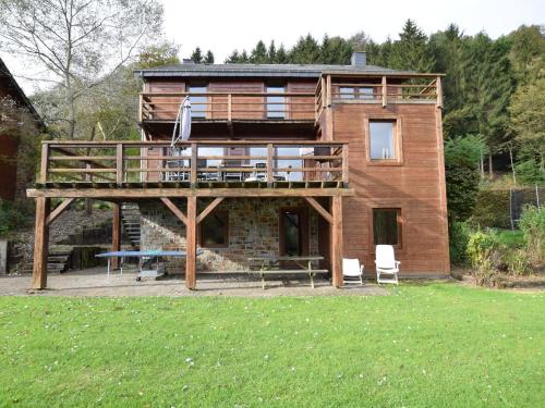 Duplex Chalet in Rendeux Ardennes with Sauna and Terrace في Verpré: منزل خشبي كبير مع شرفة وحديقة