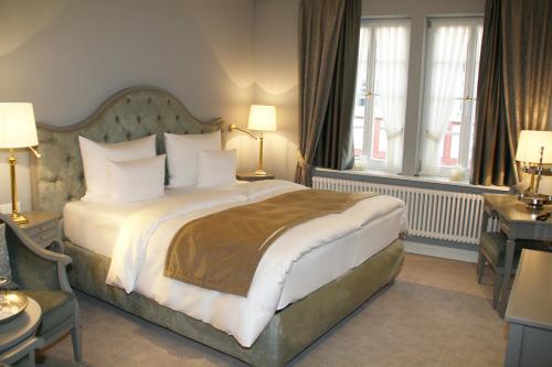 a bedroom with a large bed and a chair at Romantik Hotel Zur Glocke in Trier