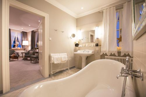 a white bathroom with a tub and a sink at Romantik Hotel Zur Glocke in Trier