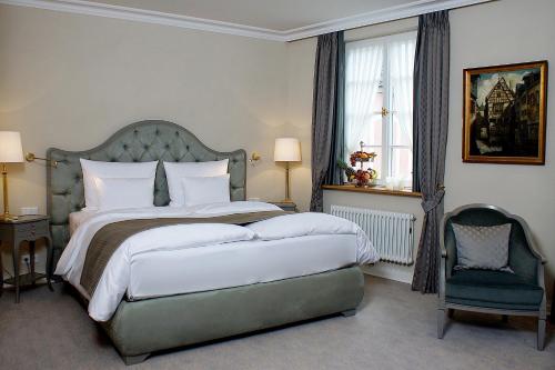 a bedroom with a large bed and a chair at Romantik Hotel Zur Glocke in Trier