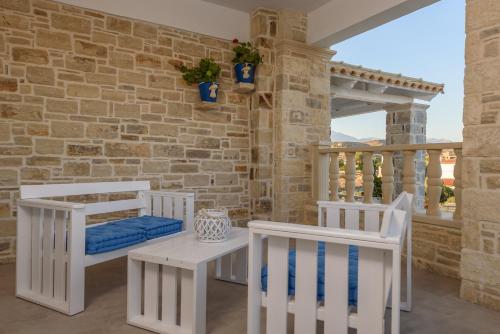 une terrasse couverte avec des chaises blanches et un mur en briques dans l'établissement Aristodimos Luxury Suite, à Kalamaki