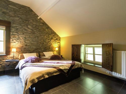 1 dormitorio con cama y pared de piedra en Luxury home in Gedinne with bubble bath and sauna en Gedinne