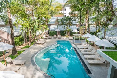 an image of a pool with lounge chairs and umbrellas at Deevana Krabi Resort in Ao Nang Beach