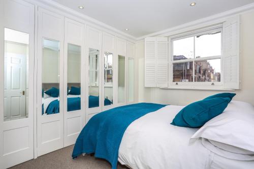 ロンドンにあるAhometorent - Charming Apartmentの白いベッドルーム(青い枕の大型ベッド付)