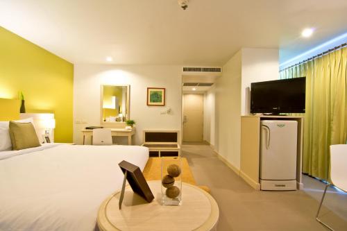 a hotel room with a bed and a flat screen tv at Sunshine Vista Hotel in Pattaya Central
