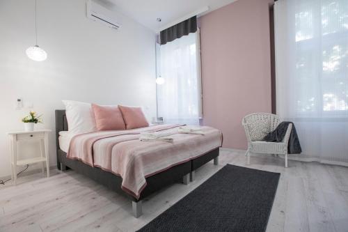 a bedroom with a bed and a chair and a window at City Center Stúdió Apartmanok in Szeged